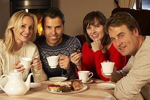 Group Of Middle Aged Couples Enjoying Tea And Cake Together