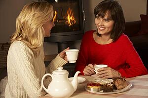Two Middle Aged Women Enjoying Tea And Cake Together