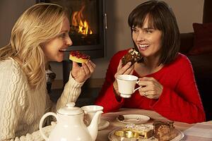 Two Middle Aged Women Enjoying Tea And Cake Together