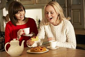 Two Middle Aged Women Enjoying Tea And Cake Together