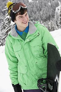 Teenage Boy With Snowboard On Ski Holiday In Mountains