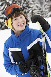 Young Boy With Snowboard On Ski Holiday In Mountains