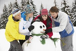 Group Of Friends Building Snowman On Ski Holiday In Mountains