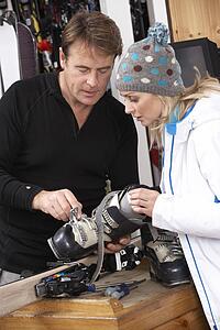 Sales Assistant Helping Advising Female Customer On Ski Boots In Hire Shop