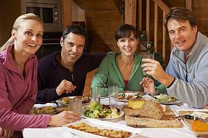 Group Of Friends Enjoying Meal In Alpine Chalet Together