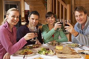 Group Of Friends Enjoying Meal In Alpine Chalet Together