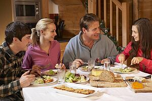Teenage Family Enjoying Meal In Alpine Chalet Together