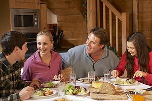 Teenage Family Enjoying Meal In Alpine Chalet Together