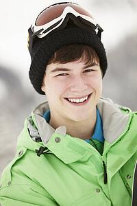 Teenage Boy With Snowboard On Ski Holiday In Mountains