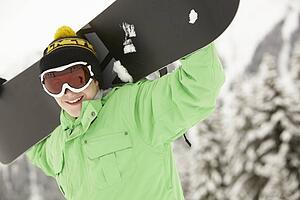 Teenage Boy With Snowboard On Ski Holiday In Mountains