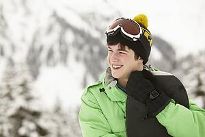 Teenage Boy With Snowboard On Ski Holiday In Mountains