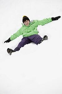Teenage Boy Making Snow Angel On Slope