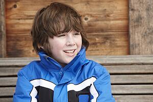 Boy Dressed For Cold Weather Sitting On Wooden Bench