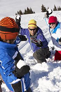 Family Having Snowball Fight On Ski Holiday In Mountains