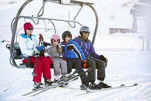 Family Getting Off chair Lift On Ski Holiday In Mountains