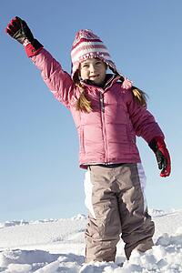 Young Girl Playing In Snow On Holiday In Mountains