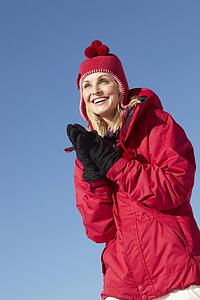 Woman Standing In Snow Wearing Warm Clothes On Ski Holiday In Mountains