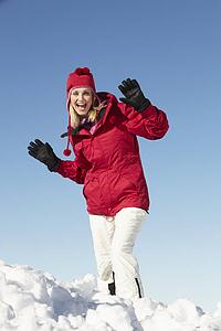 Woman Standing In Snow Wearing Warm Clothes On Ski Holiday In Mountains