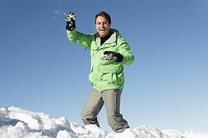 Man About To Throw Snowball Wearing Warm Clothes On Ski Holiday In Mountains
