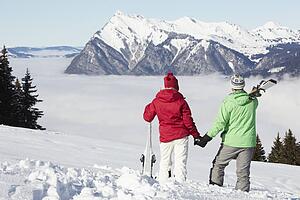 Couple Admiring Mountain View Whilst On Ski Holiday In Mountains