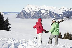Couple Admiring Mountain View Whilst On Ski Holiday In Mountains