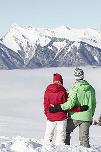Couple Admiring Mountain View Whilst On Ski Holiday In Mountains