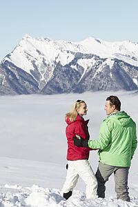 Couple Admiring Mountain View Whilst On Ski Holiday In Mountains