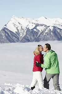 Couple Admiring Mountain View Whilst On Ski Holiday In Mountains