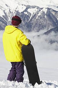 Teenage Snowboarder Admiring Mountain View Whilst On Ski Holiday In Mountains