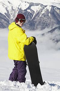 Teenage Snowboarder Admiring Mountain View Whilst On Ski Holiday In Mountains