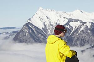 Teenage Snowboarder Admiring Mountain View Whilst On Ski Holiday In Mountains