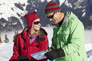 Couple Looking At Map Whilst On Ski Holiday In Mountains