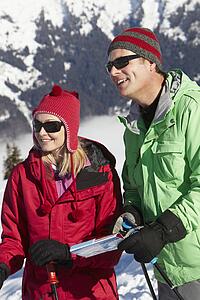 Couple Looking At Map Whilst On Ski Holiday In Mountains