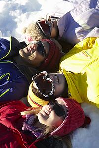 Overhead View Of Teenage Family Lying In Snow On Ski Holiday In Mountains