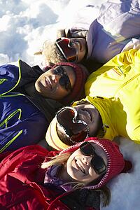 Overhead View Of Teenage Family Lying In Snow On Ski Holiday In Mountains
