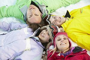 Overhead View Of Teenage Family Lying In Snow On Ski Holiday In Mountains