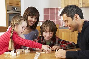 Family Playing Dominoes In Kitchen