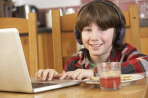 Boy Using Laptop Whilst Eating Breakfast