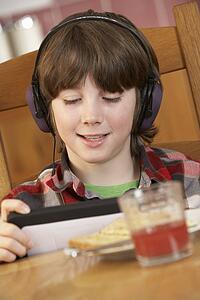 Boy Using Tablet Computer Whilst Eating Breakfast