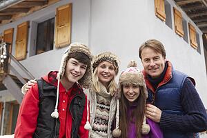 Portrait Of Family Standing Outside Chalet On Ski Holiday