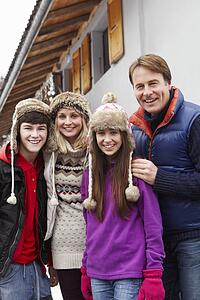 Portrait Of Family Standing Outside Chalet On Ski Holiday