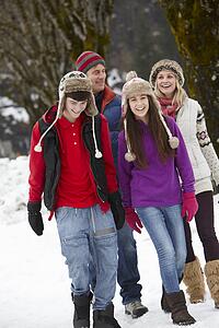 Teenage Family Walking Along Snowy Street In Ski Resort