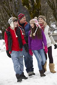 Teenage Family Walking Along Snowy Street In Ski Resort