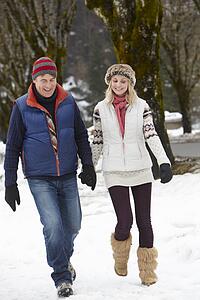 Couple Walking Along Snowy Street In Ski Resort