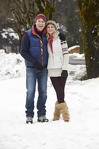 Couple Walking Along Snowy Street In Ski Resort