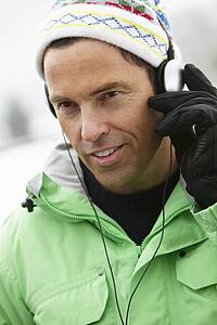 Man Wearing Headphones And Listening To Music Wearing Winter Clothes In Snowy Landscape