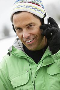 Man Wearing Headphones And Listening To Music Wearing Winter Clothes In Snowy Landscape