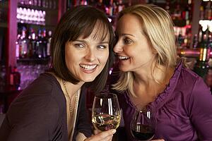 Two Women Enjoying Drink Together In Bar