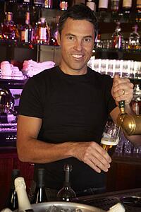 Portrait Of Barman Standing Behind Bar Pouring Beer