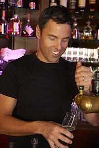 Portrait Of Barman Standing Behind Bar Pouring Beer